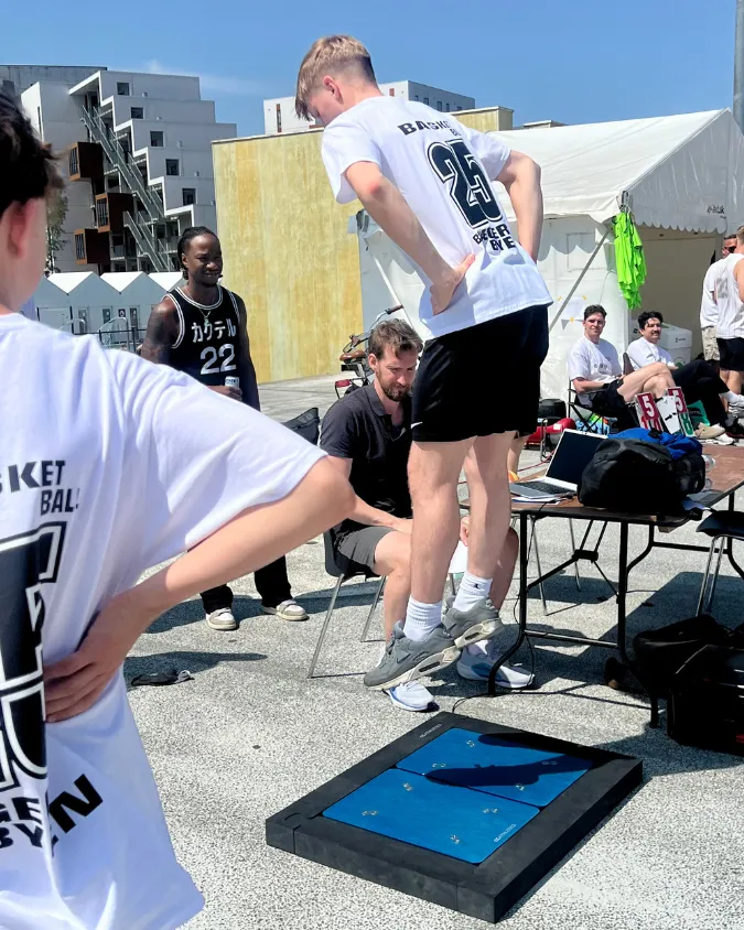 An athlete performing a jump test on a force plate at an outdoor event.
